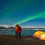 couple hugs as they watch the northern lights dazzle across iceland