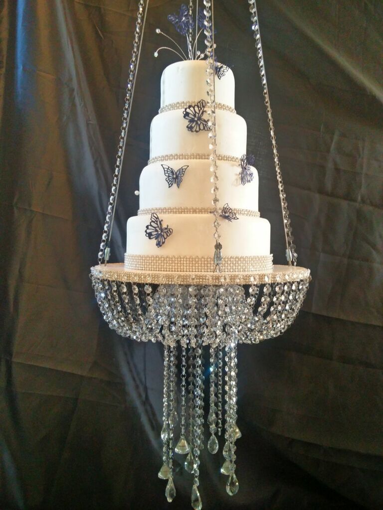 Floating chandelier wedding cake stand supporting four-tier cake