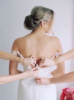 Ladies Help Bride With Updo and Dress With Buttons into Her Wedding Gown