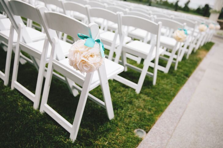 White rose kissing balls were hung off the white folding ceremony chairs with a bright teal ribbon.