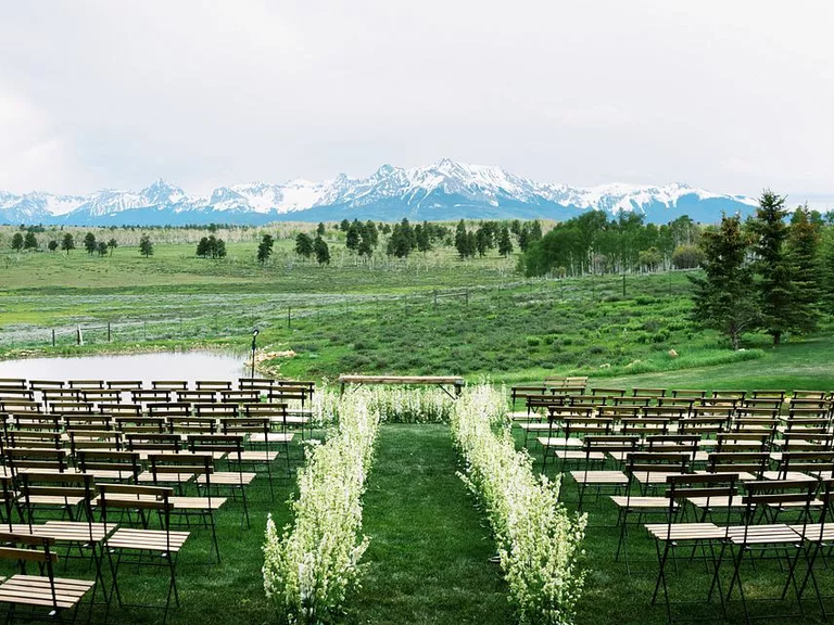 A ceremony site outdoors with a floral walkway down the aisle.