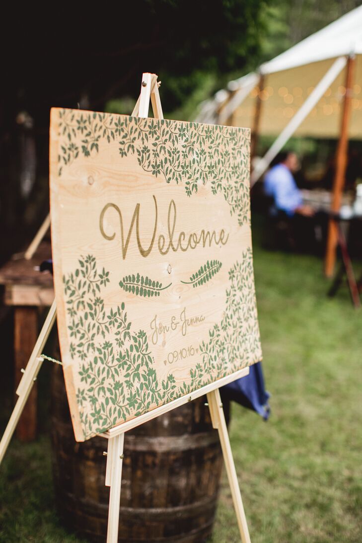 Jenna and Jon made all the decorations for the intimate woodland affair, including the wooden welcome sign at the entrance to the reception tent. To capture the organic, nature-inspired theme, the sign featured fern and vine flourishes in a soft shade of green.