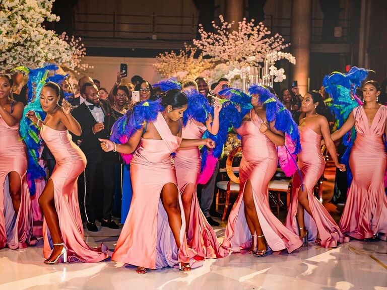 Bridal party dancing in pink dresses and wearing colorful angel wings.